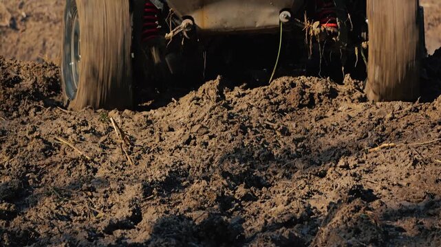 Close up of powerful 4x4 vehicle stuck in thick brown mud. Wheels spin, splashing dirt during extreme motorsport competition. Dynamic action shot captures challenge and power of off roading