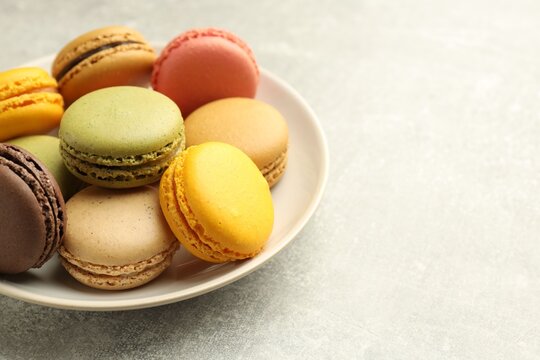 Yummy colorful macarons on light grey table, closeup. Space for text