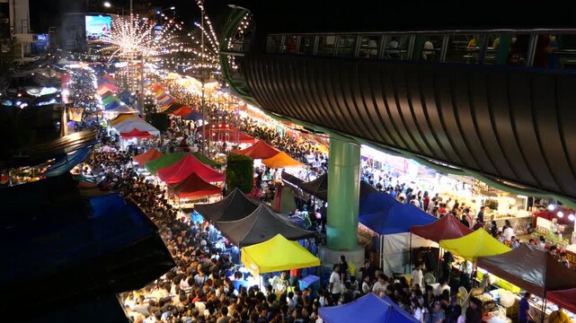 Crowd of Asians at night market. Phra Samut Chedi Temple fair. It is one of the biggest temple fairs in Thailand. People can easily get there by BTS city train from Bangkok. 