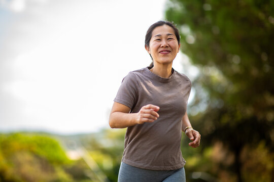 East asian woman jogging outdoors for healthy active lifestyle
