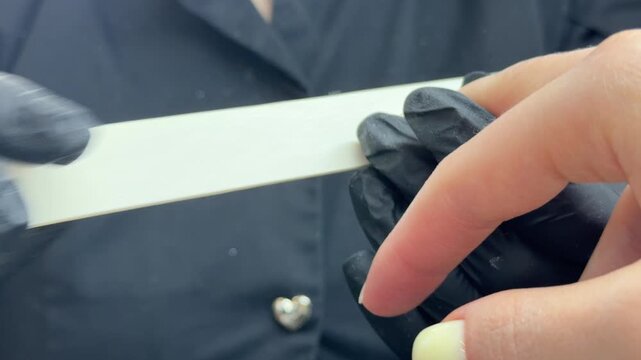 Manicurist filing nails of client