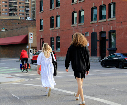 Un homme v&ecirc;tu de noir et une femme v&ecirc;tue de blanc traversent une rue de la ville de Calgary.