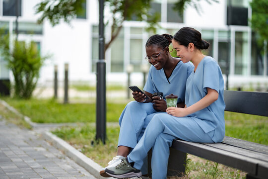 Healthcare workers using smart phone during coffee break outdoors