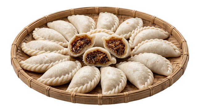 Traditional steamed coconut filled dumplings called pitha in woven bamboo tray.