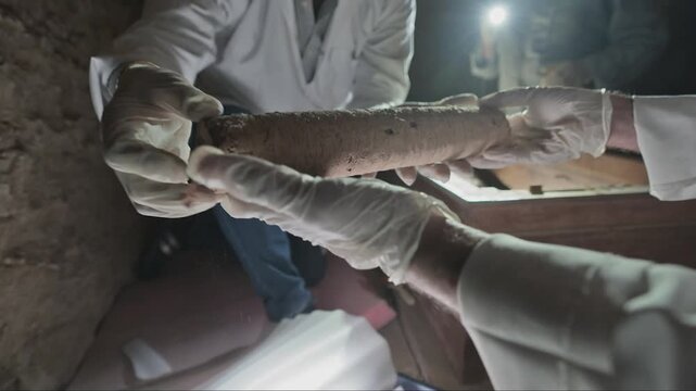 Scientists carefully removing a mummified relic from a sarcophagus during an excavation in Egypt