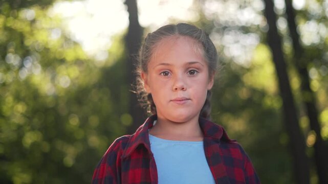 Young girl showing emotion changes outdoor in park. Child displays happy smile and different expressions. Kid with braided hair showing emotions. Girl in nature expresses various feeling outdoors.