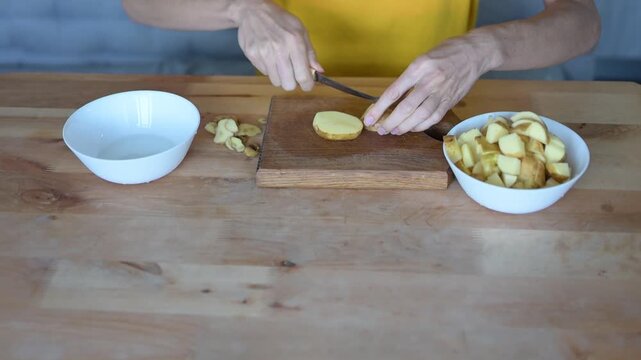 Woman peeling and cutting potato on wooden board during home cooking Full HD preparation video