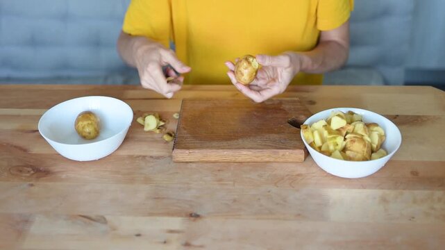 Woman peeling and cutting potato on wooden board during home cooking preparation video Full HD