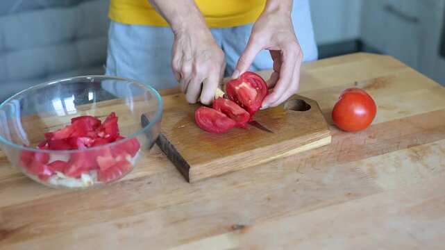 Woman cutting ripe tomato on wooden board in home kitchen preparing fresh vegetable salad video Full HD