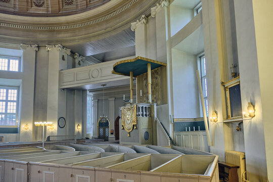 Karlskrona, Sweden - 14 September 2025: View of the interior of the Church of the Holy Trinity German church featuring the ornate pulpit, wooden pews, and classical columns.