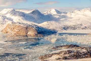 Scenic Greenlandic aerial landscape with icy fjord, snow-covered mountain peaks, ice floes and golden winter light, Narsarsuaq, Kujalleq, Greenland © vadim.nefedov