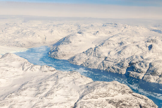 Aerial view of snowy arctic mountains, icy fjord water, sea ice and Greenland ice cap landscape, South Greenland