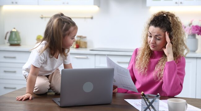 Woman with her daughter working at wooden table in home office