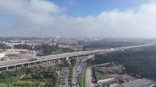 Vis&atilde;o a&eacute;rea do Rodoanel no Alto Tiet&ecirc;, SP, com viadutos, pistas, ve&iacute;culos, al&ccedil;as e vegeta&ccedil;&atilde;o, destacando infraestrutura, mobilidade e transporte regional.