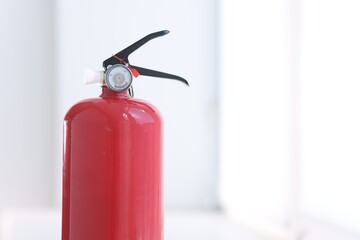 Obraz premium One red fire extinguisher near white wall indoors, closeup. Space for text