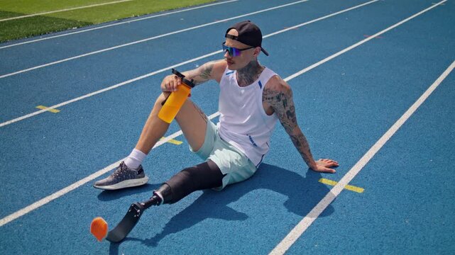 Trained runner with bionic prosthesis drinks water on racetrack