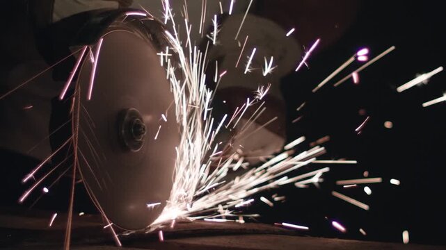 Grinding wheel cutting steel, sparks fly, closeup workshop shot with rotating disc shaving metal, warm embers scattering