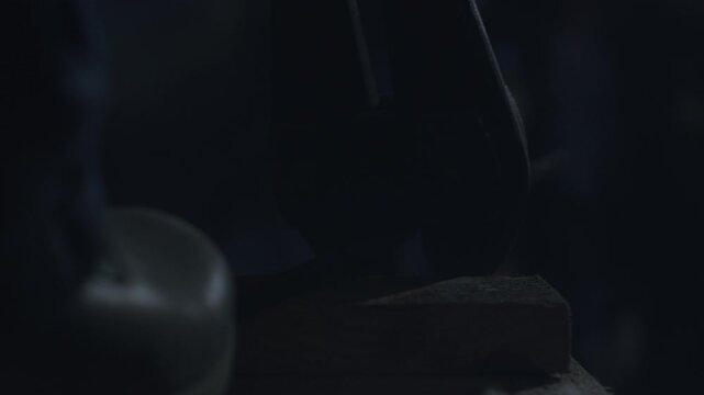 Closeup hammer striking metal anvil, lowkey lighting smoky atmosphere, heavy impact and industrial grit, faint ember glow