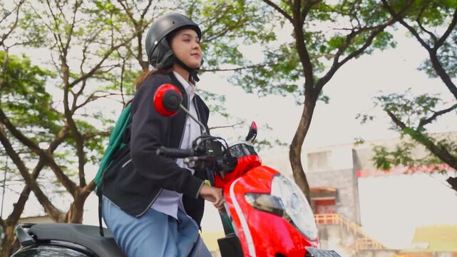 Early in the clip, a young woman stands on the left side of the frame beside a bright red scooter, carefully fastening or adjusting her helmet with a calm