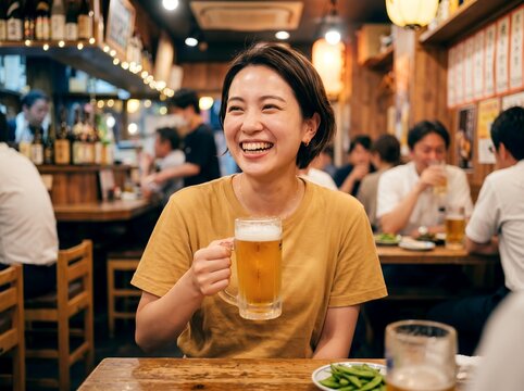 賑やかな居酒屋でビール片手に満面の笑みを浮かべる若い女性