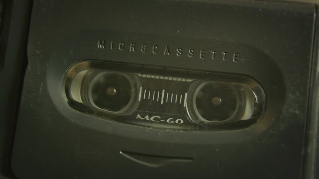 Micro cassette tape video loop. Close up shot of an old style small recording magnetic tape, commonly used by journalists in dictation and interviews