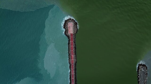Aerial zenith drone shot of Miramar Beach breakwater in Tamaulipas, where the Panuco River meets the Gulf of Mexico, creating a striking natural color division between fresh and salt water