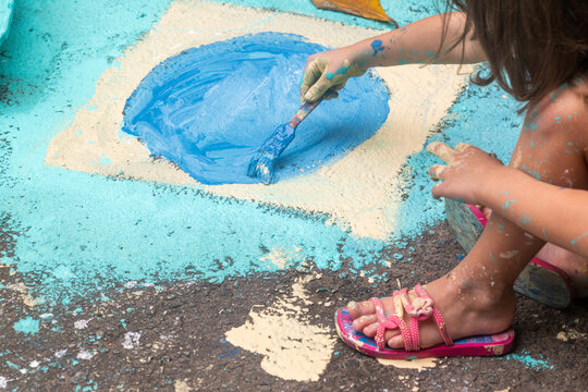 Rio de Janeiro, Brazil - 13 June 2026: View of a child painting a blue circle on the asphalt street with a brush, preparing decorations for the World Cup 2026.