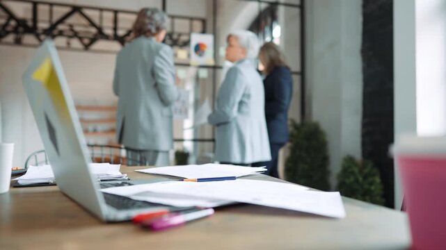 Inside modern office, elderly ladies viewing charts and diagrams on glass wall. Teamwork and brainstorm in boardroom, senior women making decisions and solving financial problem, business investments
