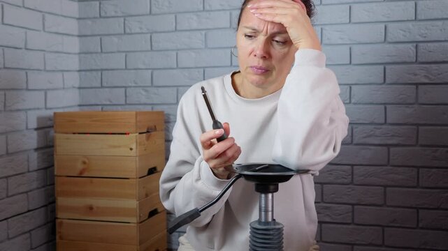 Frustrated woman failing to assemble furniture at home. Frustrated caucasian woman having problems and difficulty assembling new furniture, feeling tired and stressed while and holding a screwdriver