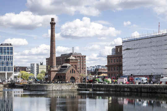 Liverpool, United Kingdom - 06 May 2026: View of The Pumphouse at Albert Dock with its iconic tall brick chimney reflected in the calm water under a cloudy sky.