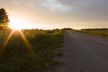 Scenic dirt road in the countryside at golden hour sunset with a bright sunburst © TerraFocus