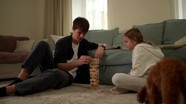 Two people are stacking blocks on the floor while a dog watches them in a living room. They enjoy the game together