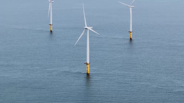 Aerial drone close up of an offshore wind turbine near Redcar Middlesbrough UK showing structure blades and base in the sea representing renewable energy generation in a clean environment