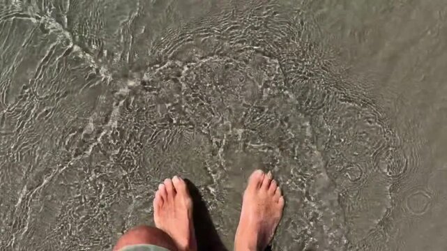Walking barefoot in to the ocean with water swirling around the feet as the waves roll in
