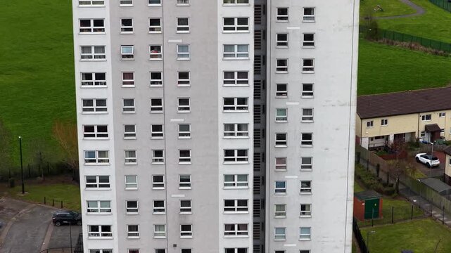 Aerial close view of tower block of apartments in Middlesbrough with surrounding houses green space and school buildings showing urban density and residential layout in the daytime in spring