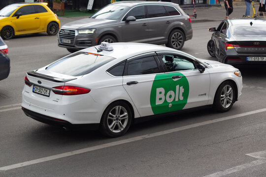 Tbilisi, Georgia - June 17, 2026: Defocused photo. White taxi car with green Bolt logo on door in traffic jam on city street. Concept of drive, road trip, speed, private transport, mobile app, parking