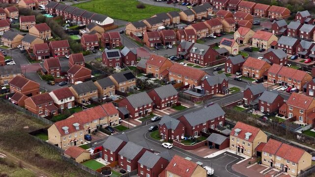 Aerial drone footage of modern housing development in Redcar North Yorkshire showing newly built family homes residential streets parked vehicles private gardens and sustainable rooftop solar panels