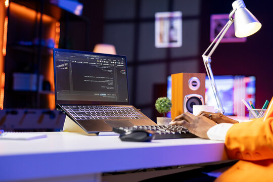 Engineer at desk typing code on notebook device, developing software programs, entering commands. Person at home fixing errors in application, implementing new features, close-up.