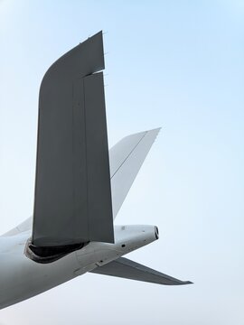 Detailed low-angle view of an aircraft tail section featuring the rudder, vertical stabilizer, horizontal stabilizer, and APU exhaust, highlighting the aerodynamic design and engineering precision
