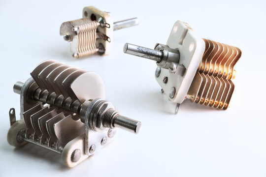 Vintage variable air capacitors on a white background used for radio frequency tuning equipment.