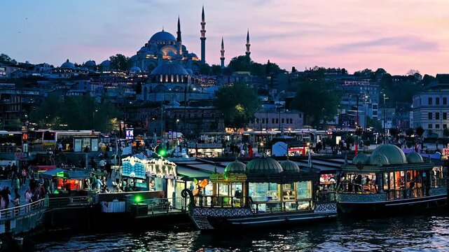 view of the historic city of istanbul near the golden horn during the evening with people walking around, a restaurant boat in the sides of the sea, mosques and with the urban area.