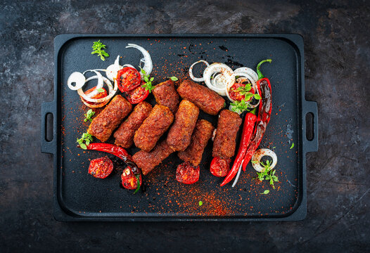 Traditional original artisan grilled cevapi made of spicy minced meat onion, roasted tomato and chili served as top view on a design plate