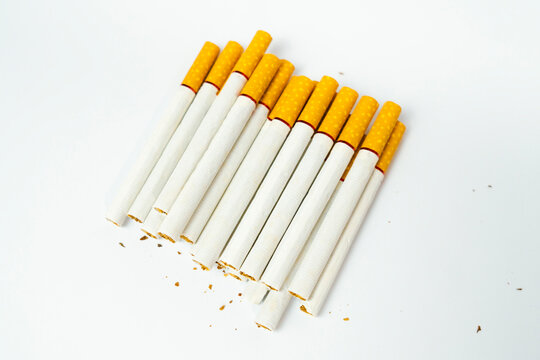Row of cigarettes with yellow filters and scattered tobacco fragments cigarette fragments nicotine addiction background