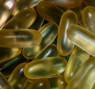 Full frame macro texture background of golden translucent omega-3 fish oil softgel capsules.