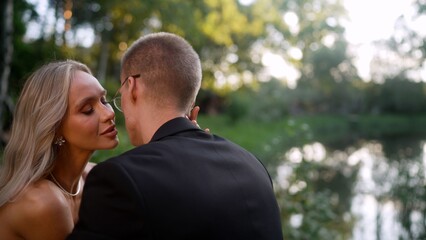 Naklejka premium romantic couple embracing near lake at sunset