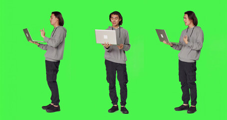 Obraz premium Model waving at online videocall on laptop, meeting with people on internet connection videoconference, asian person holding pc and chatting with friends on conference call, green screen