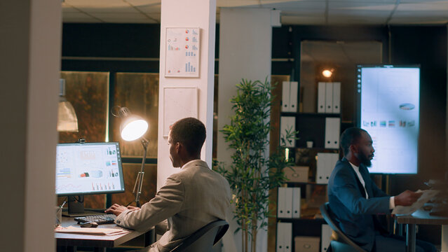 Supervisor teaching newcomer how to properly solve project tasks during inductment period in modern office, manager working nightshift helping employee during company onboarding process