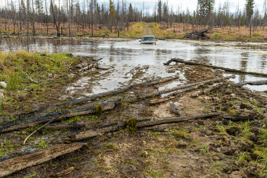 Canada, BC, Clinton.  Off road vehicle driving through deep water on flooded road in British Columbia back country.
