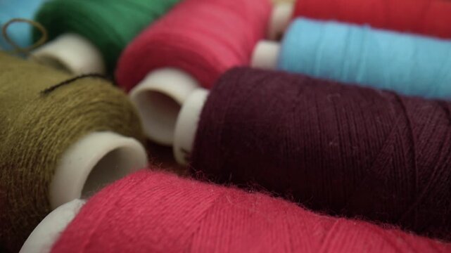 Close-up of vibrant colorful sewing thread spools on wood. Great for craft, fashion, embroidery and design projects. Macro view of textile materials.