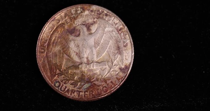   rust-covered quarter-dollar coin on a black velvet cloth, one damaged 25-cent coin covered with yellow rust and plaque, close up